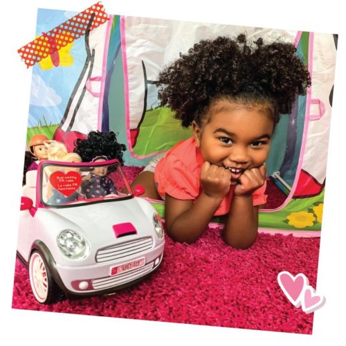 Girl with mini dolls in a toy car.
