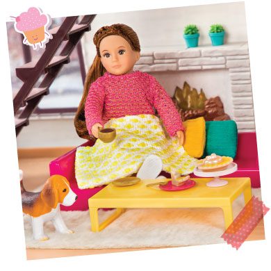 Mini doll on a couch under a blanket.